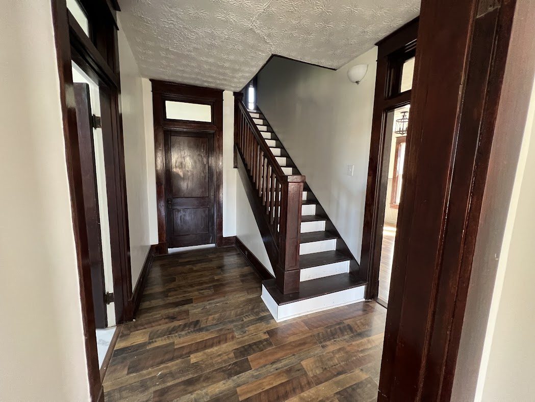 Entry hall with a staircase, dark wood trim, and plank flooring
