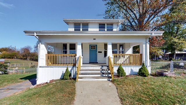 White two-story house with a front porch, teal front door, and new wood railings