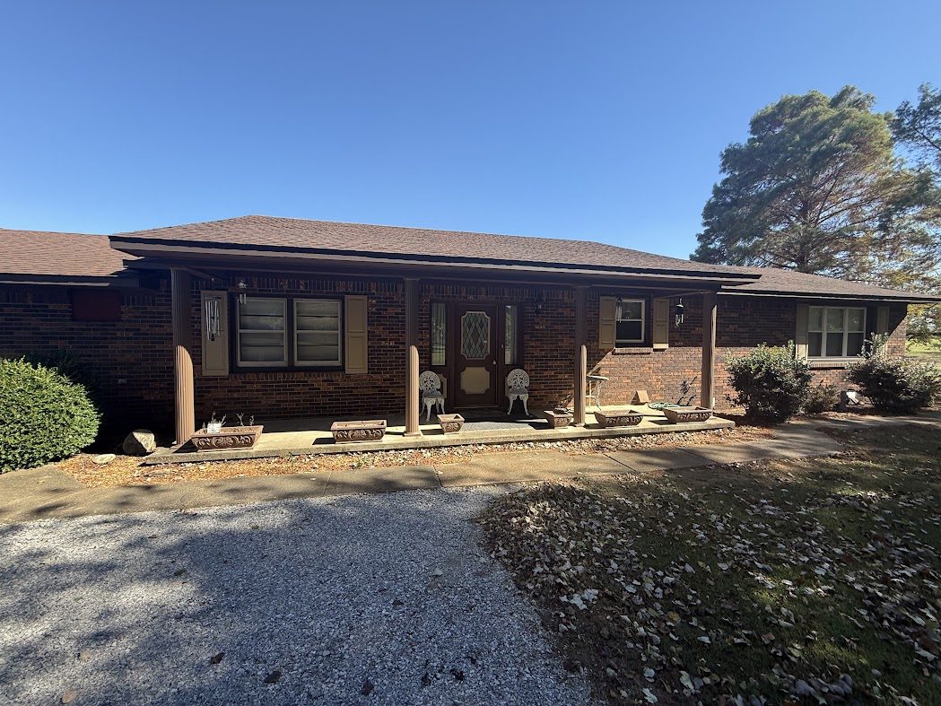 Brick ranch house with a covered front porch and a gravel drive